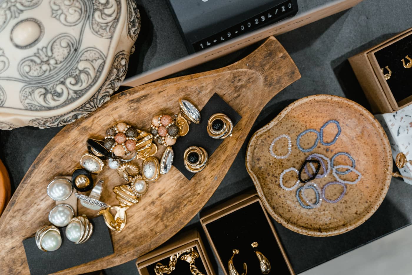Rings and bracelets laid out in a wooden tray and a ceramic dish