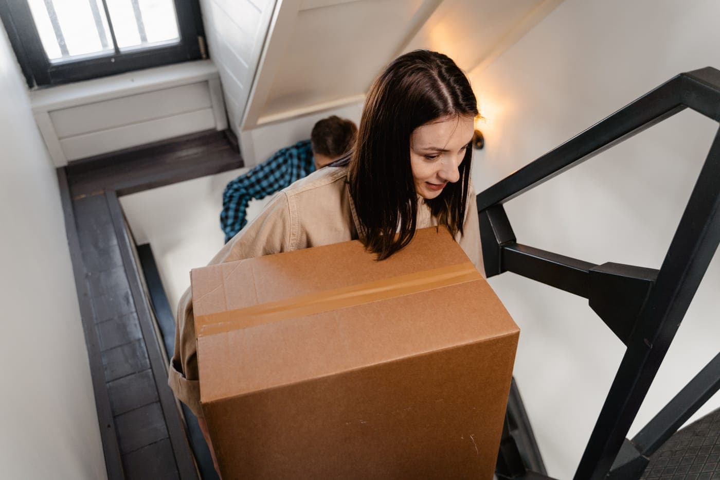 Two people carrying a large box up a staircase