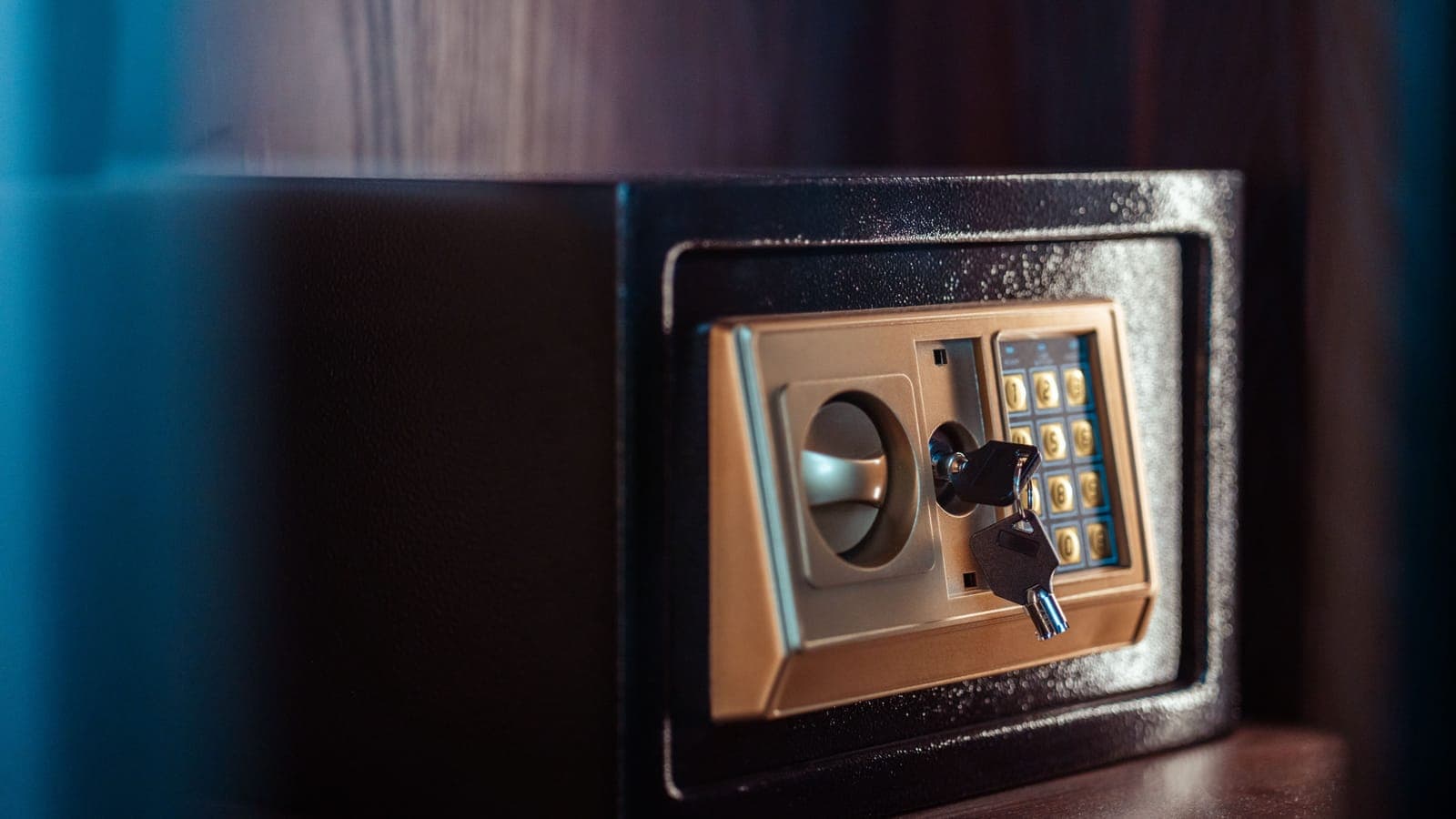 Close-up of an electronic safe door with a keypad and a key in the lock